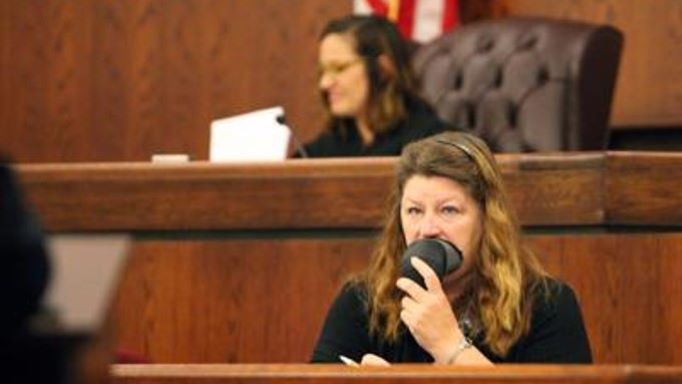 Court reporter dictating into a stenomask.  The scene is a courtroom with the judge in the background